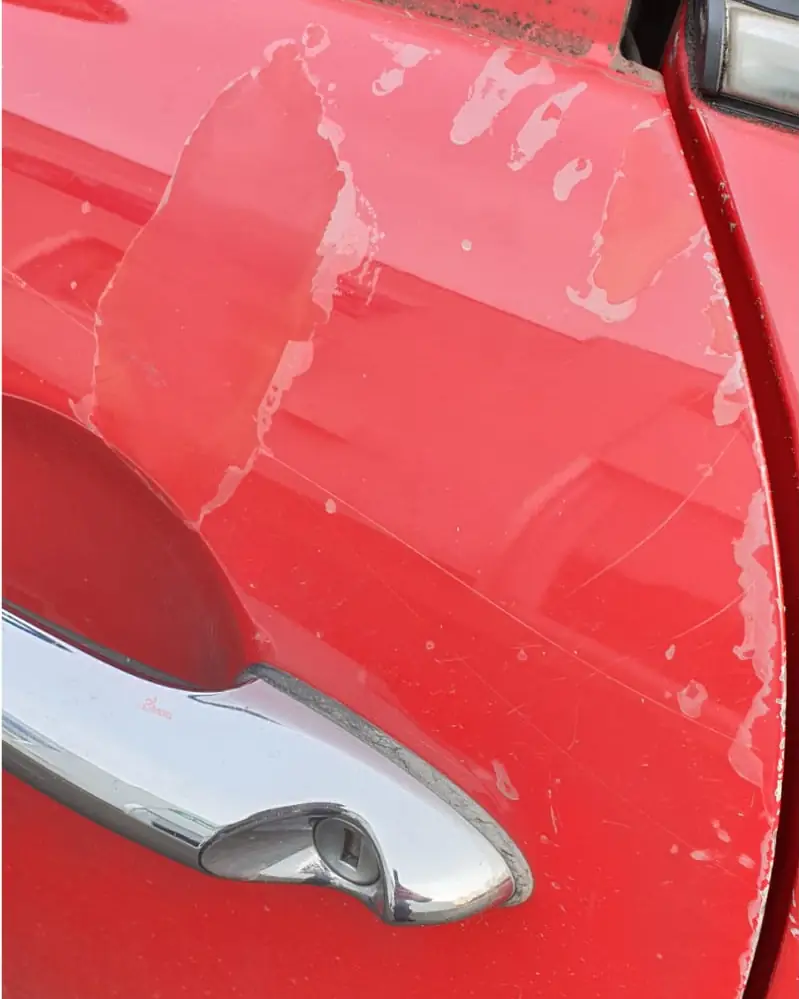 Portière rouge avant rénovation : vernis dégradé et rayures