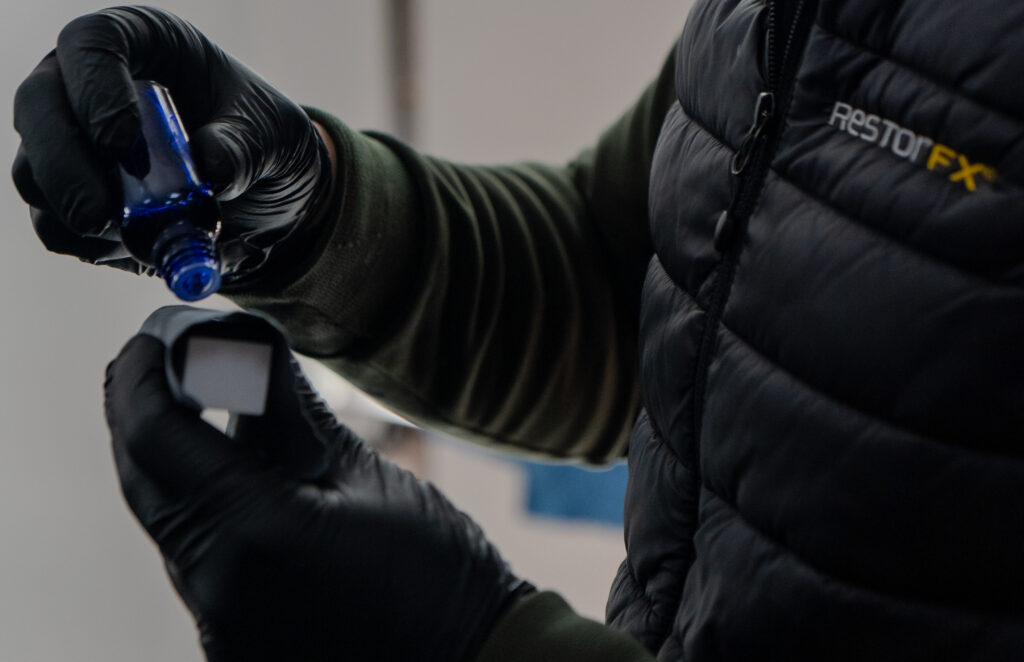 Pose du traitement céramique ClearFX par un technicien RestorFX équipée de gants et d’un applicateur bleu.
