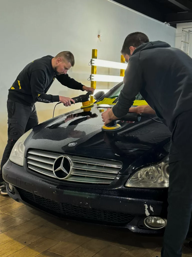 Rénovation esthétique automobile en cours : deux techniciens appliquent un traitement pour restaurer la carrosserie d’une Mercedes dans un centre RestorFX