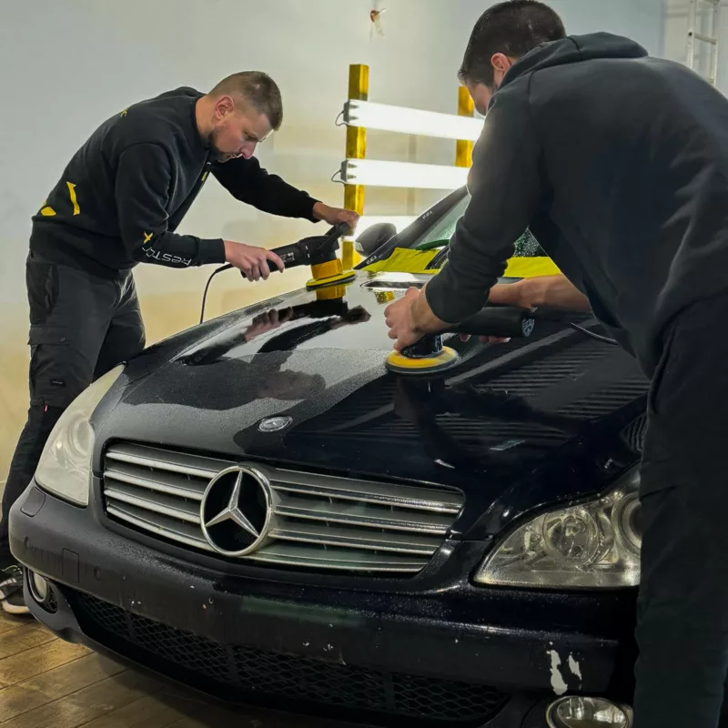 Rénovation esthétique automobile en cours : deux techniciens appliquent un traitement pour restaurer la carrosserie d’une Mercedes dans un centre RestorFX