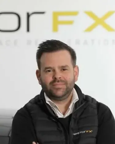 Nicolas Delahay, CEO de RestorFX France, souriant devant le mur de marque RestorFX